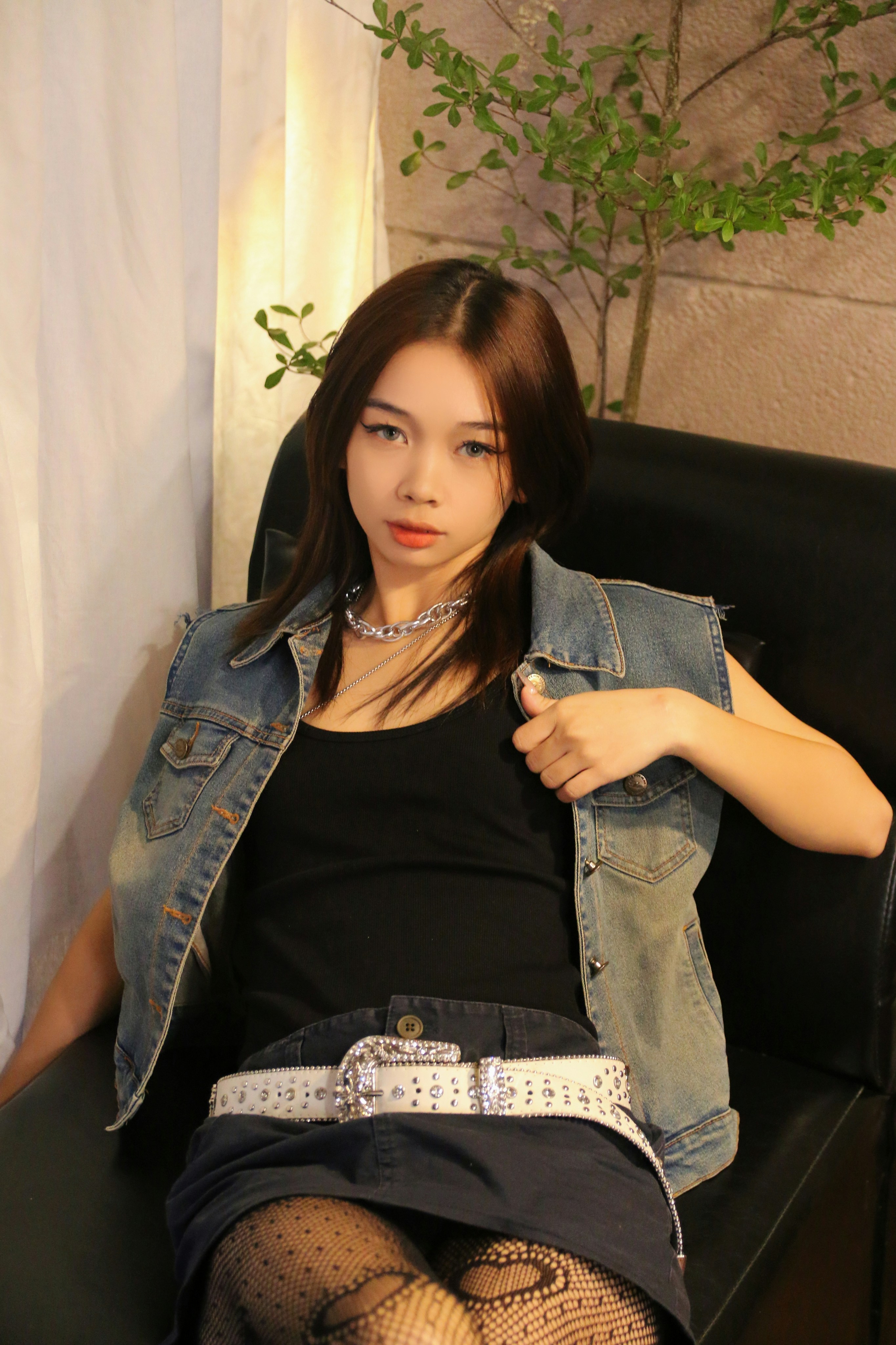 a woman sitting on a couch wearing a jean jacket