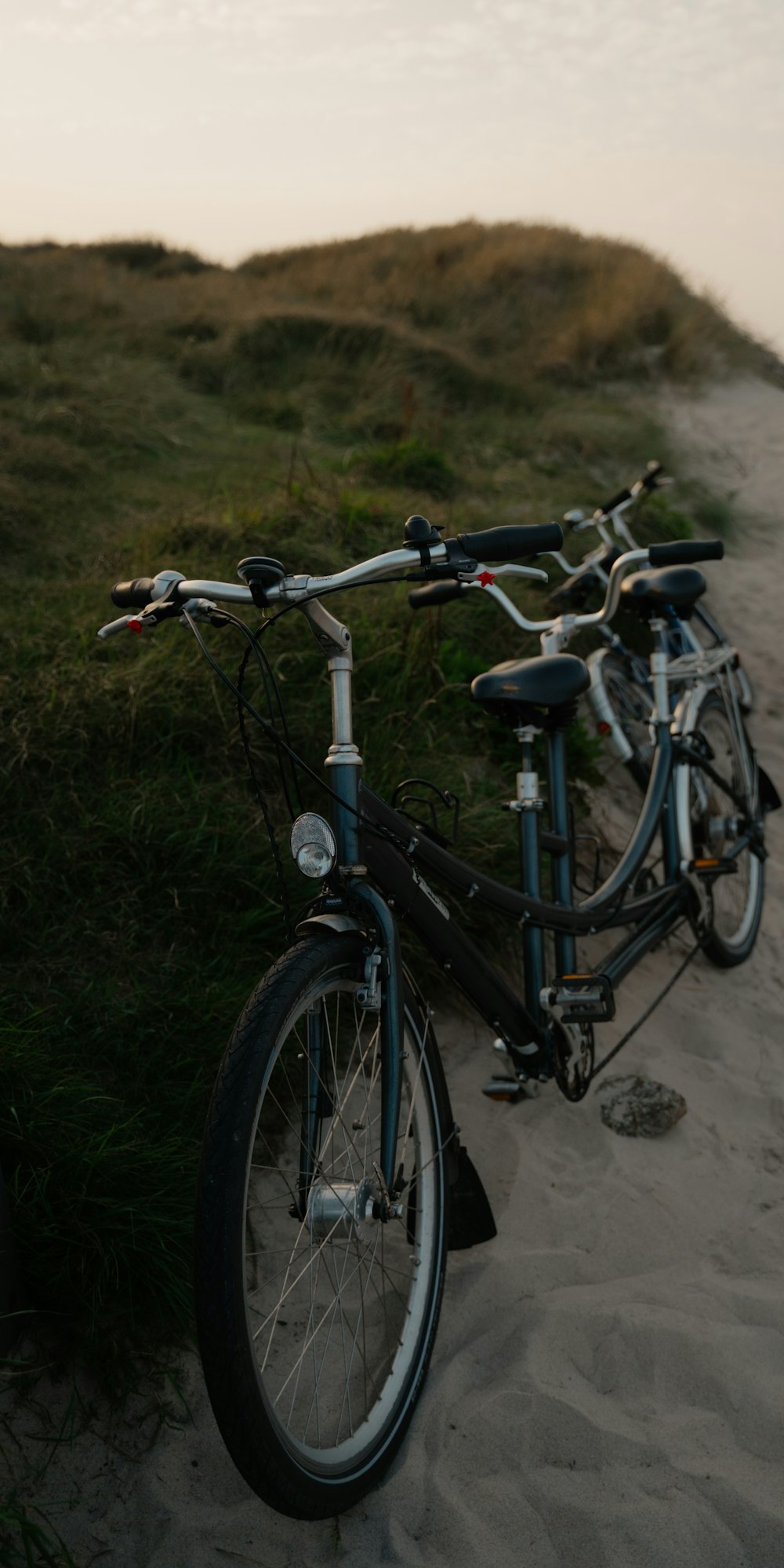 a bike parked on a beach next to a grassy hill