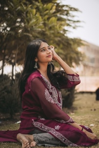 a woman sitting on the ground in a purple dress