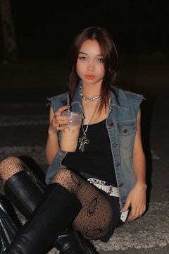a woman sitting on the ground holding a drink