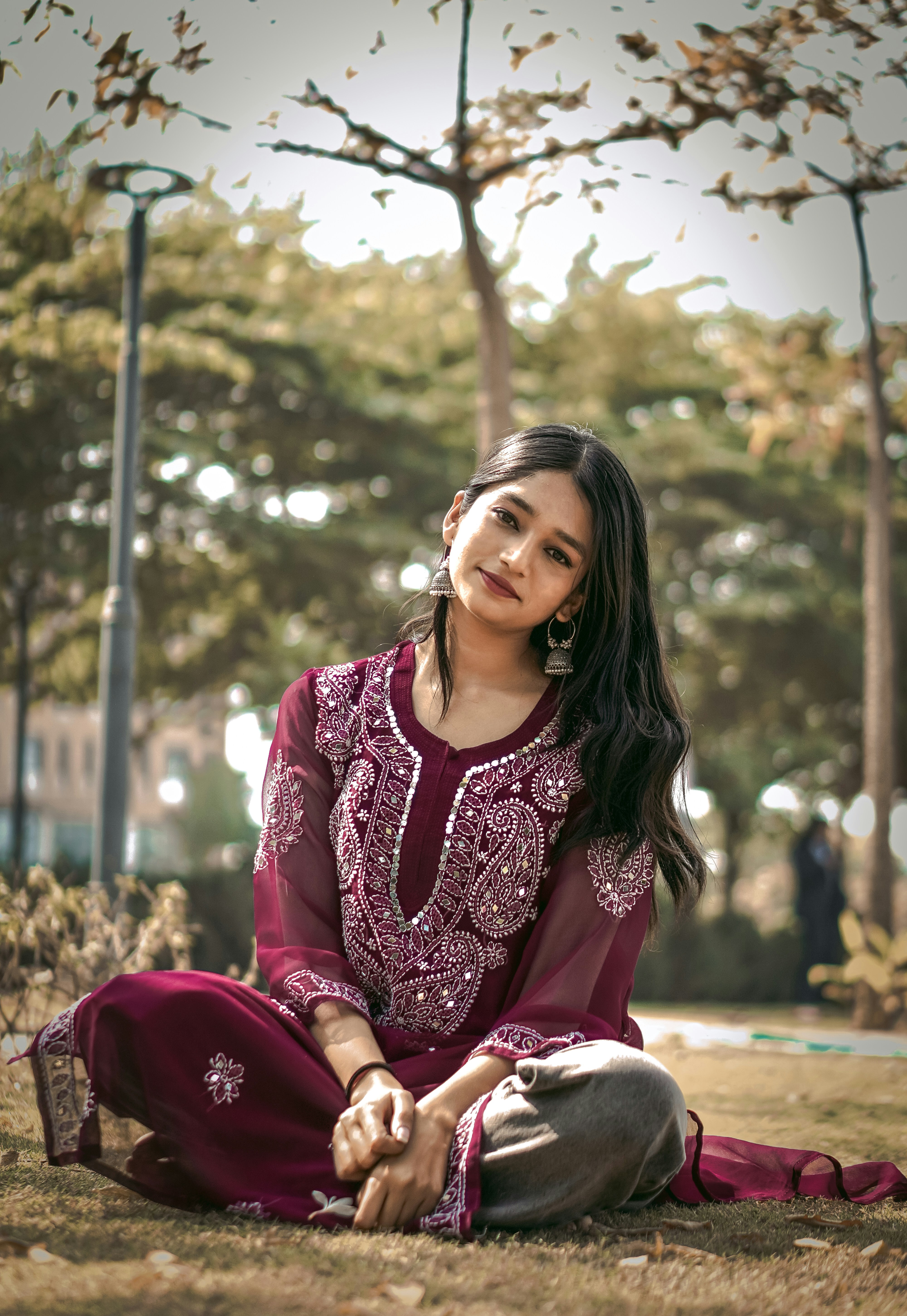 a woman sitting on the ground in a park
