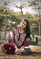 a woman sitting on the ground in a park