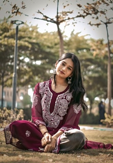 a woman sitting on the ground in a park