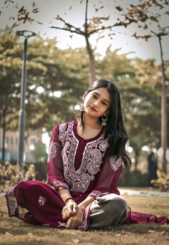 a woman sitting on the ground in a park
