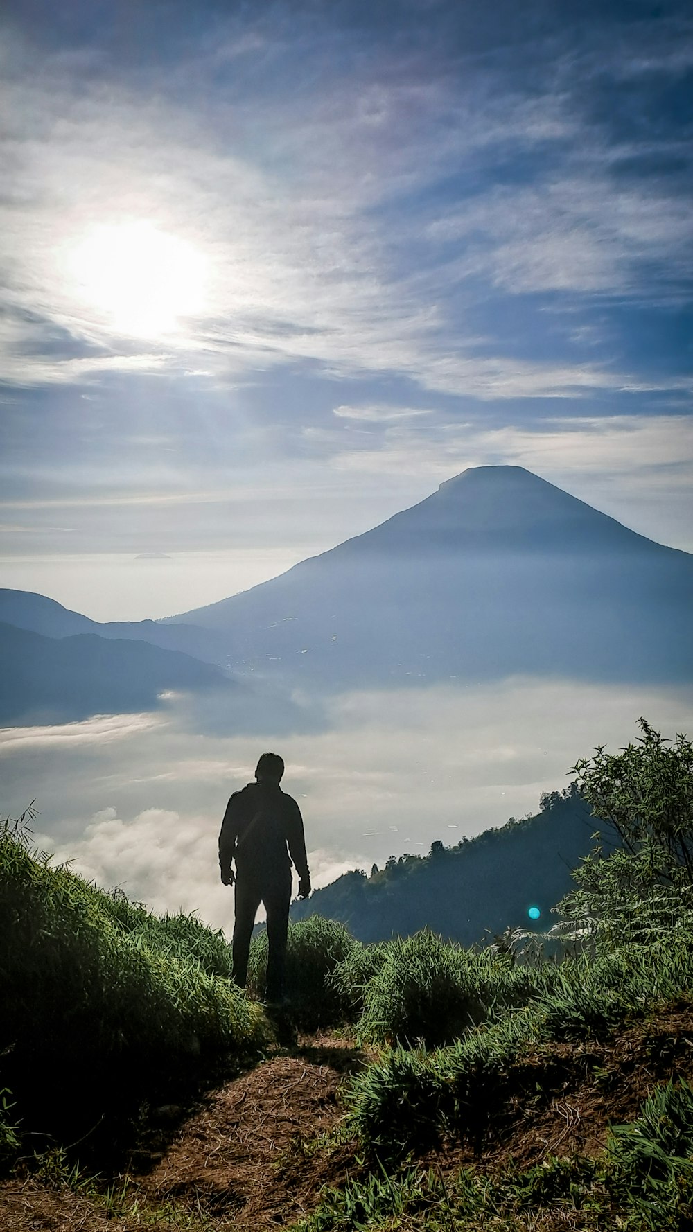 a man standing on top of a lush green hillside