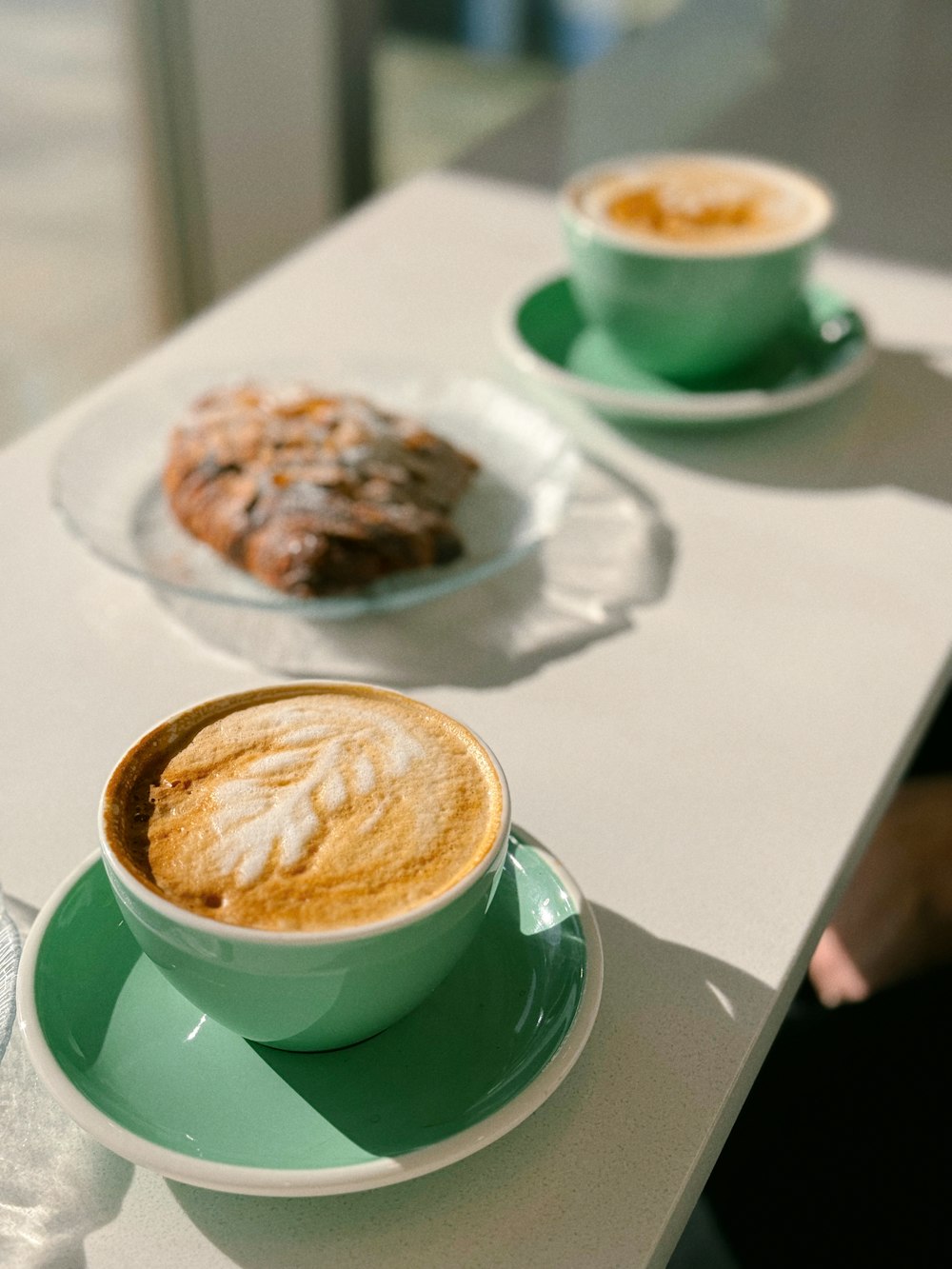 two cups of coffee and a pastry on a table