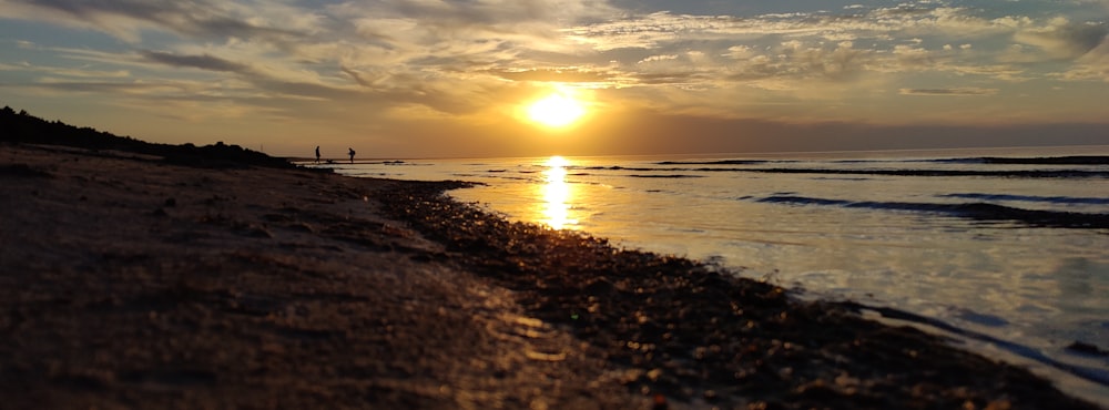 the sun is setting over the ocean on the beach