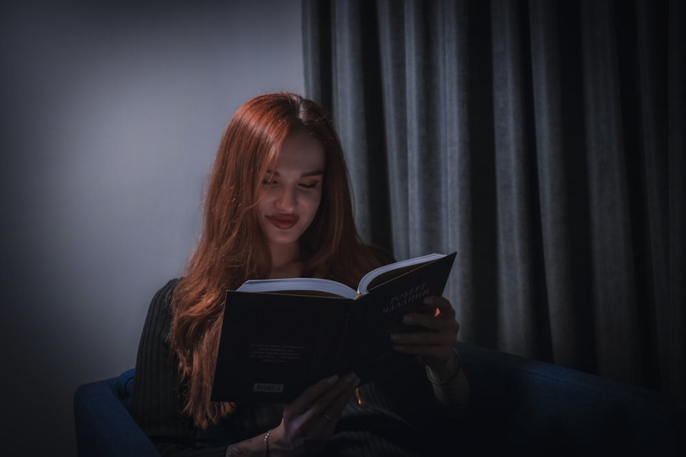 a woman sitting on a couch reading a book