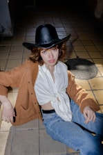 a woman sitting on the ground wearing a hat