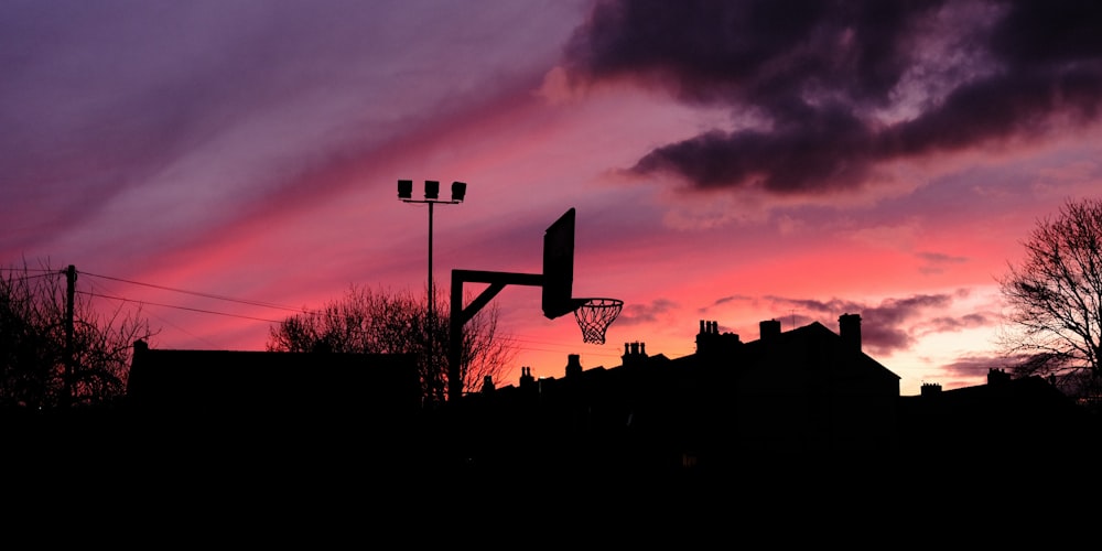 a basketball hoop is silhouetted against a sunset