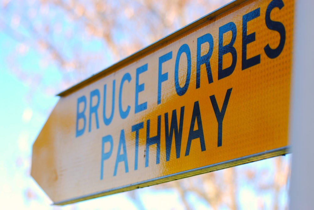 a close up of a street sign with trees in the background