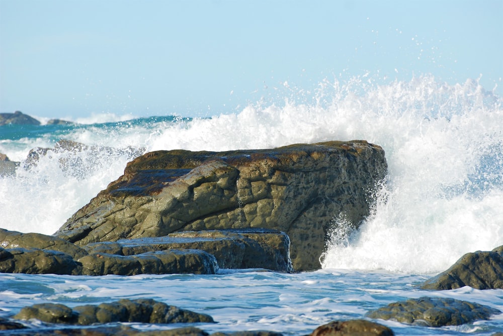 una persona in piedi su una roccia vicino all'oceano