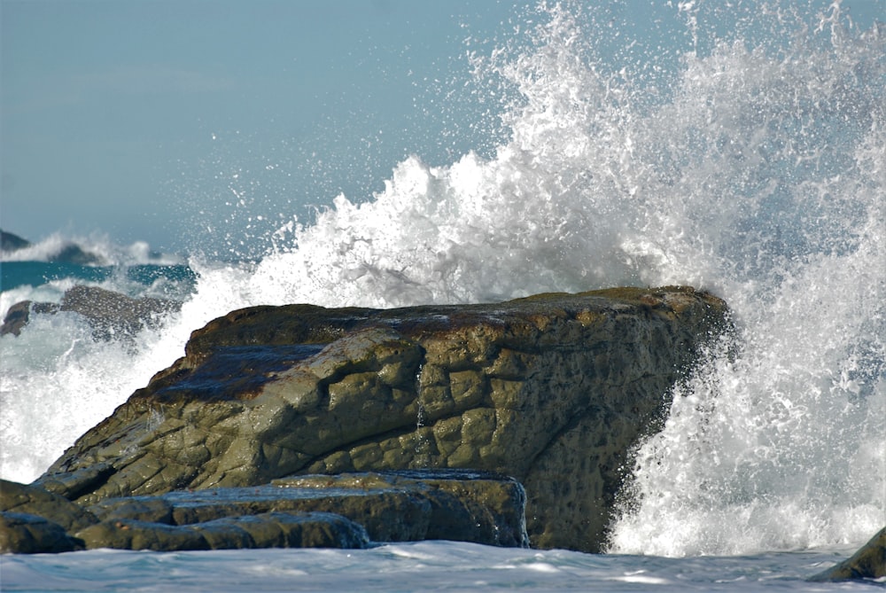 Eine große Welle bricht über einen Felsen im Ozean