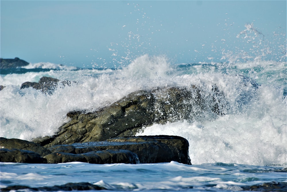 Eine Welle bricht gegen einen Felsen im Ozean
