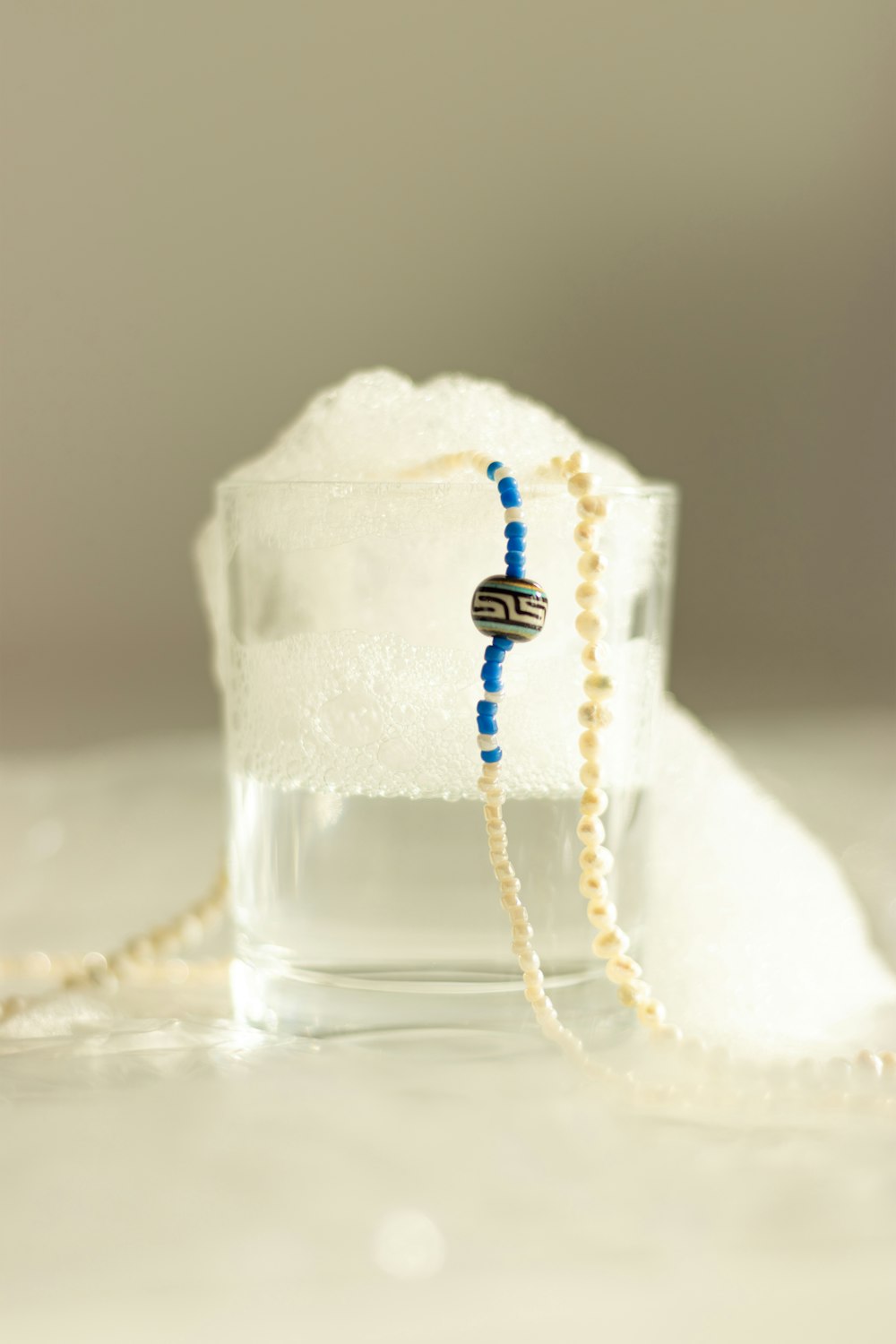 a beaded necklace sitting on top of a glass of water