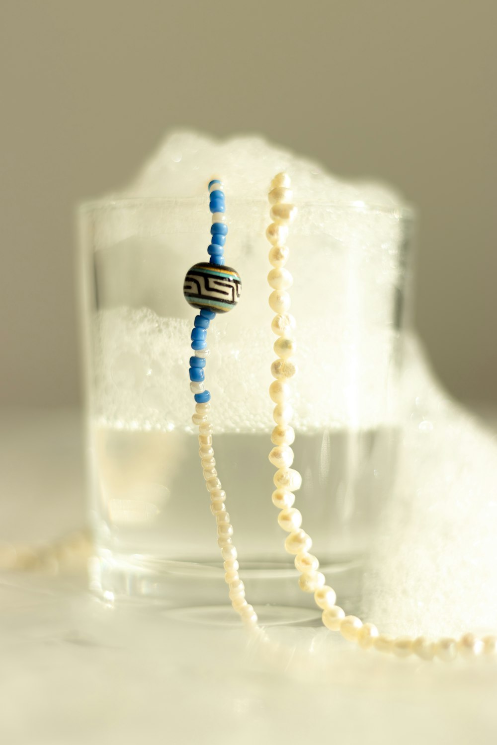 a beaded necklace sitting on top of a glass of water