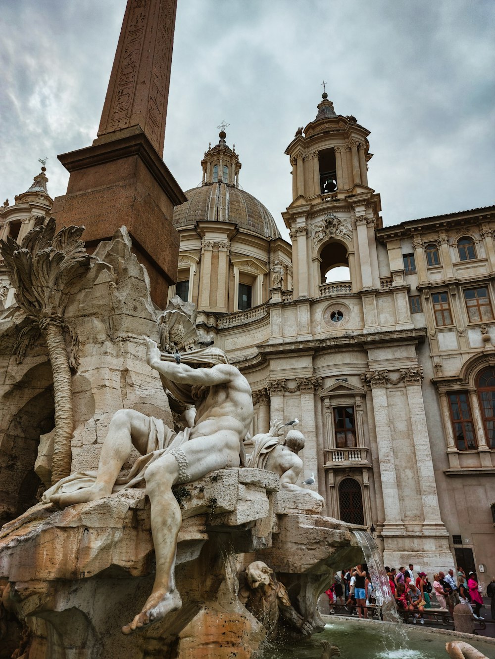 a fountain in front of a building with a clock tower in the background