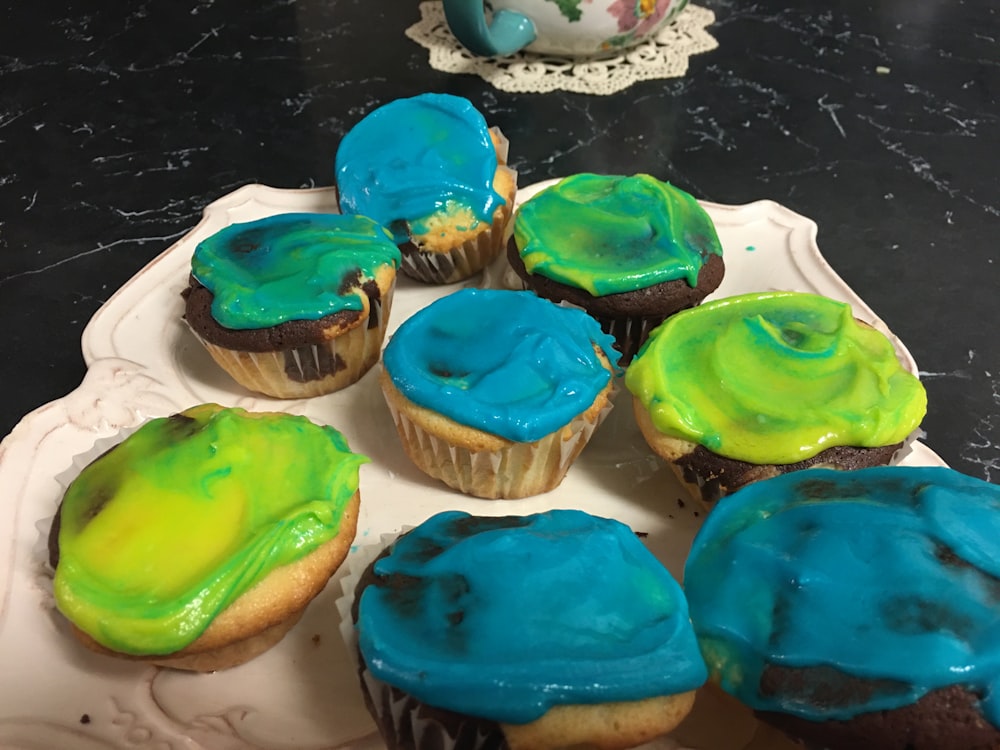 a plate of cupcakes with blue and green frosting
