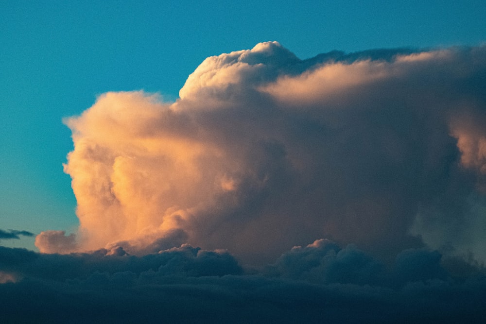 a large cloud in the sky with a plane in the distance