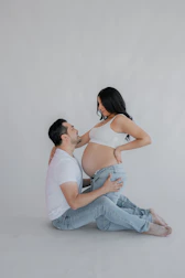 a pregnant woman sitting on the floor next to a man