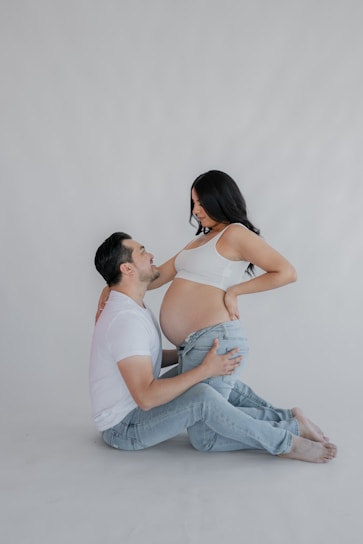 a pregnant woman sitting on the floor next to a man