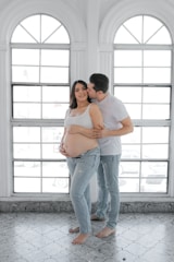 a pregnant couple standing in front of a window