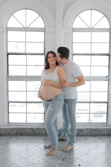 a pregnant couple standing in front of a window