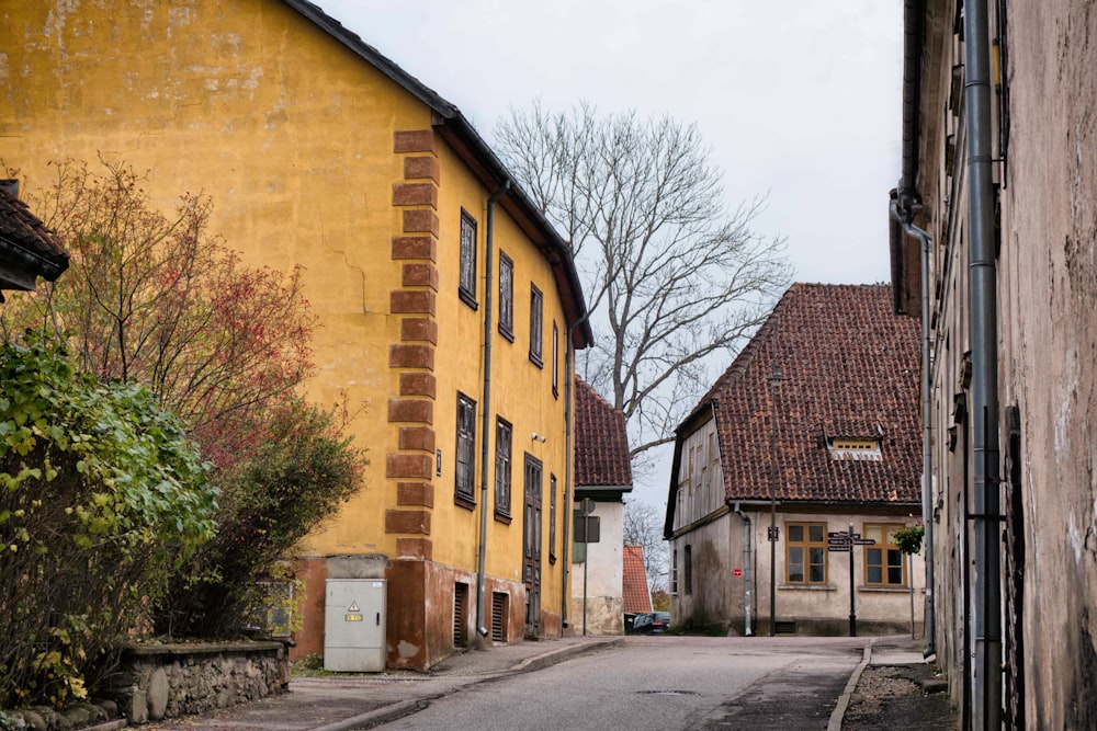 a narrow street with a yellow building in the background