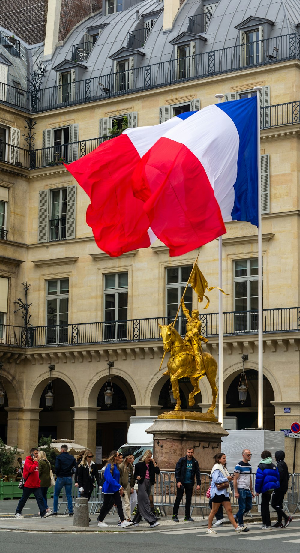 a group of people walking across a street next to a flag