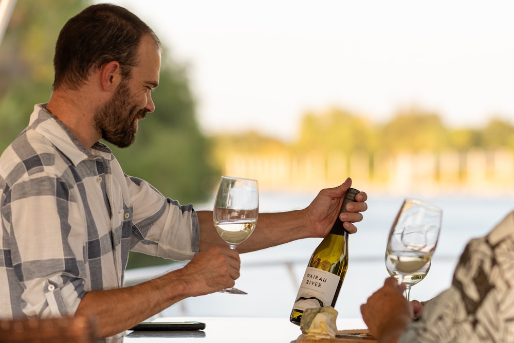 a man holding a bottle of wine and a glass of wine