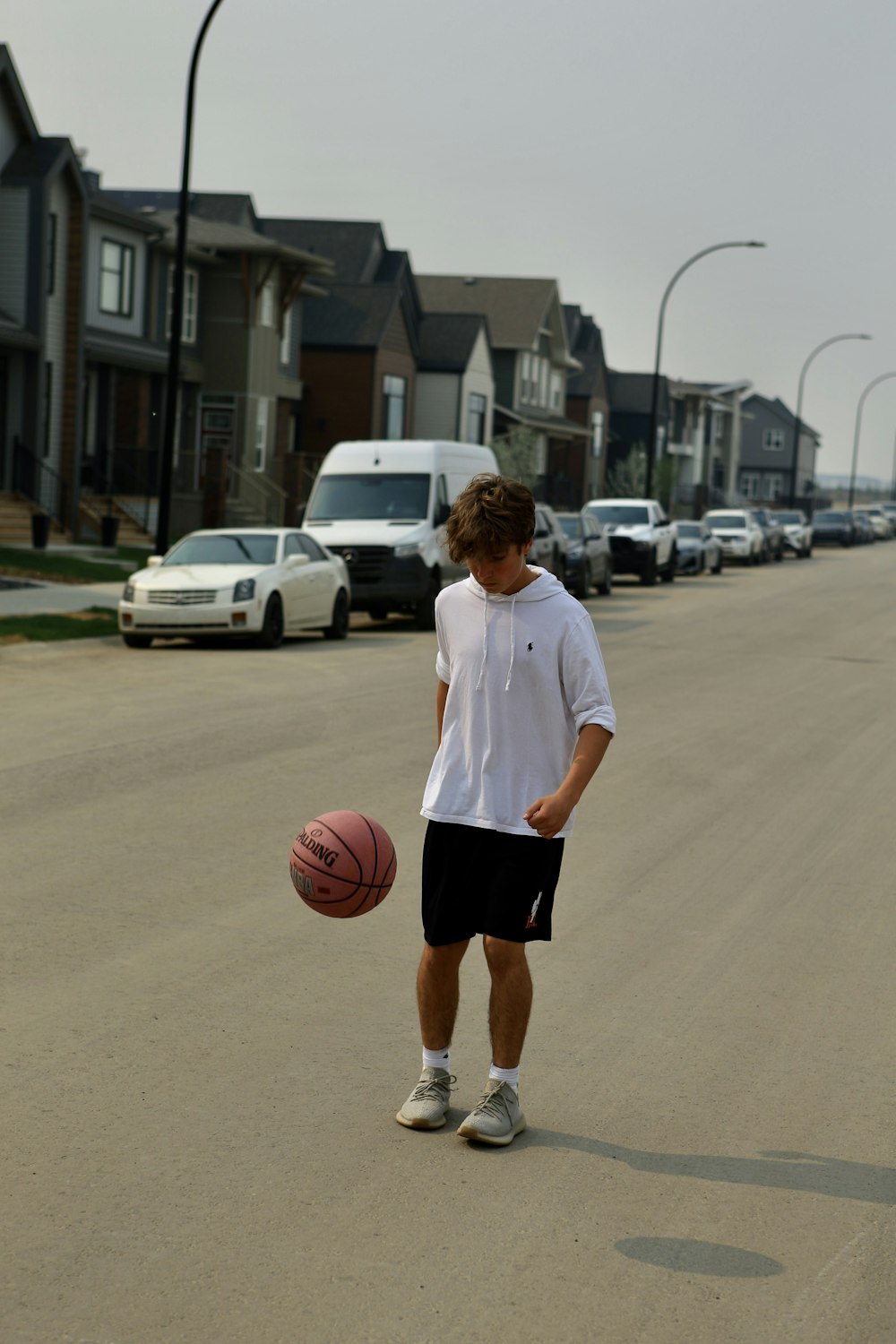 a young man holding a basketball on a street