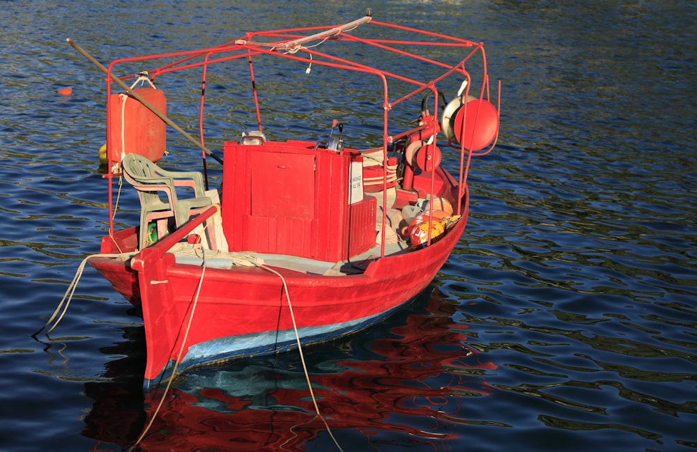a red boat floating on top of a body of water