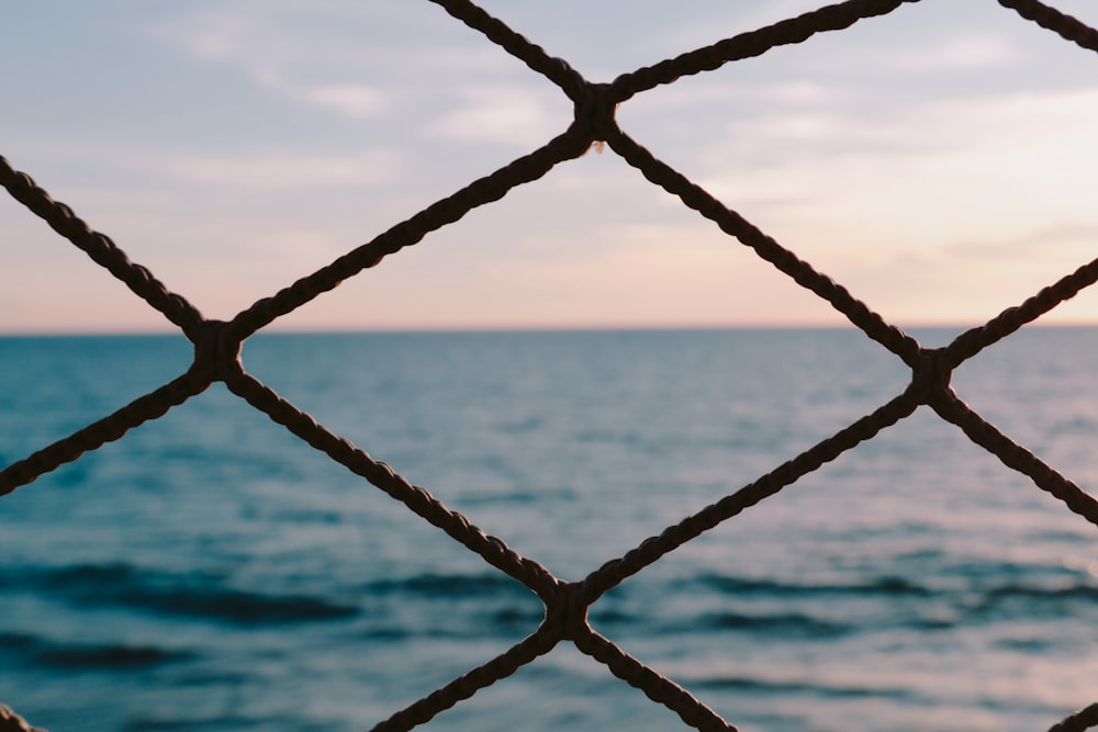 a view of the ocean through a chain link fence