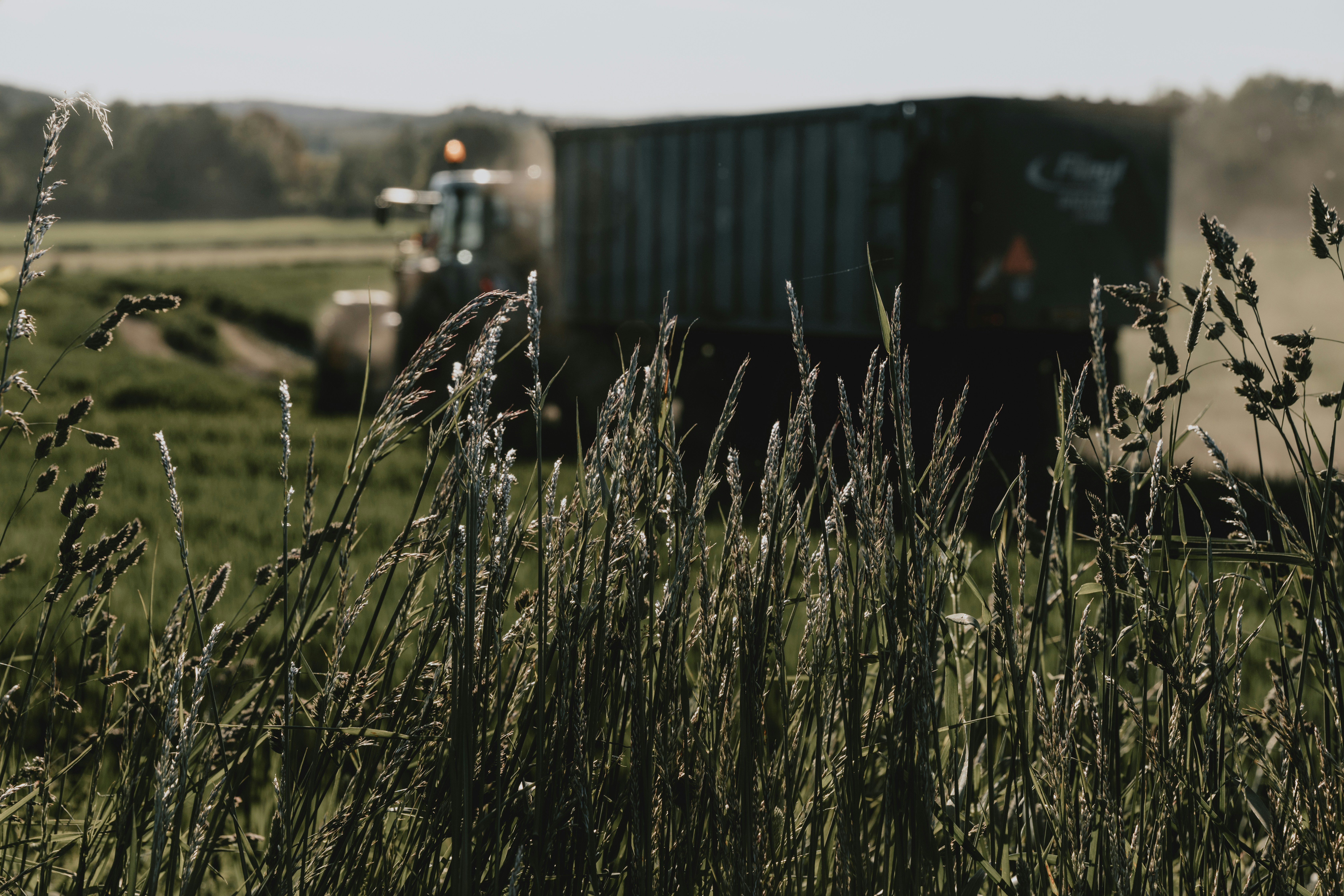Blurred moving tractor on meadow during harvest