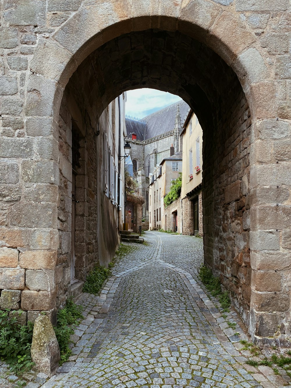 uma rua de paralelepípedos com um arco de pedra