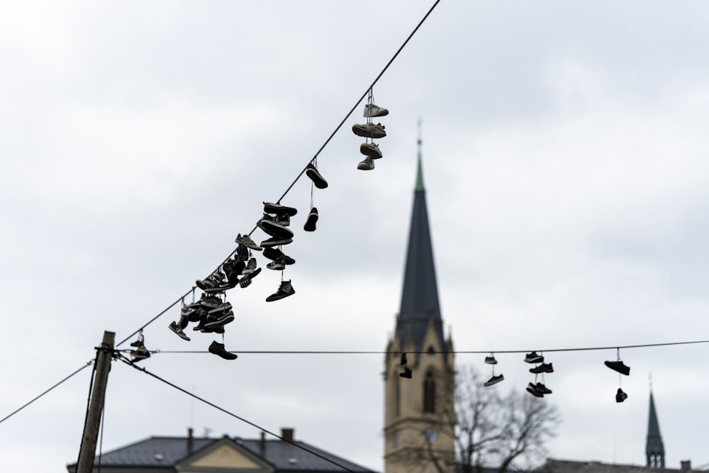 a line of shoes hanging from a power line with a church in the background