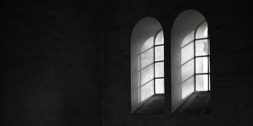 two windows in a dark room with light coming through them