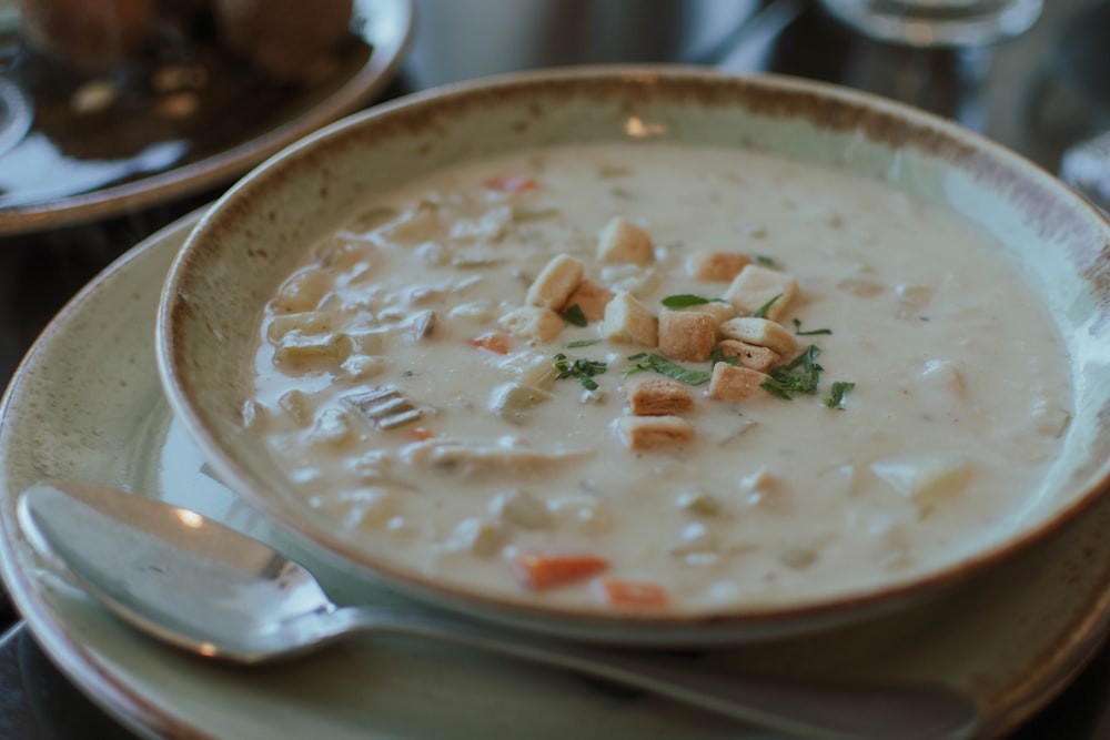 a bowl of soup on a plate with a spoon