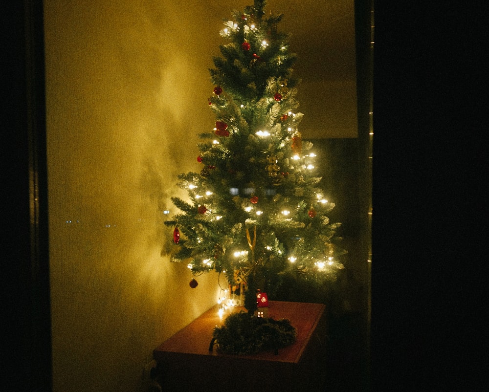 a lit christmas tree in a corner of a room