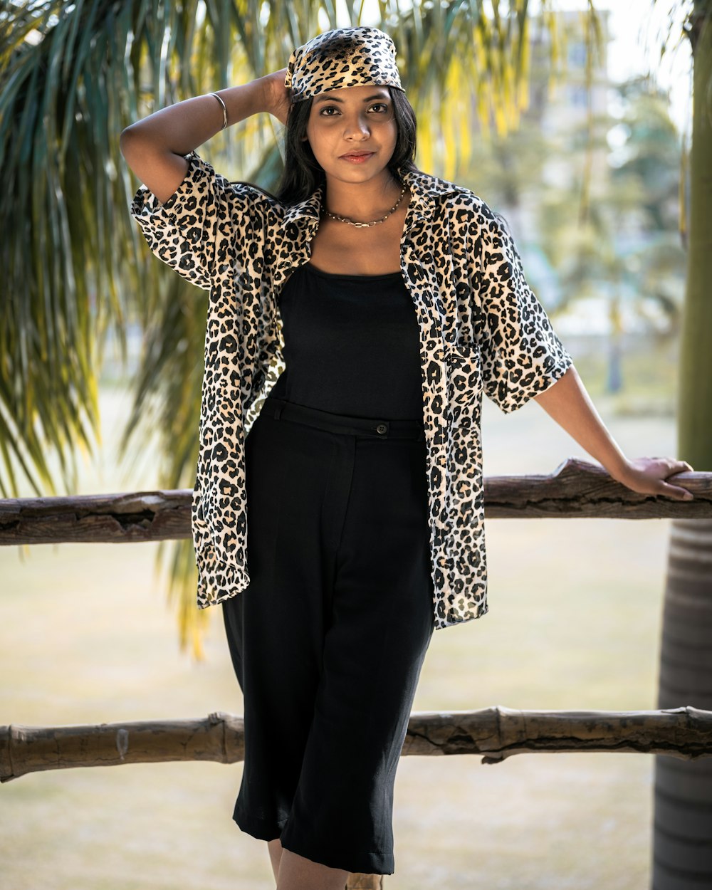 a woman in a leopard print jacket leaning on a fence