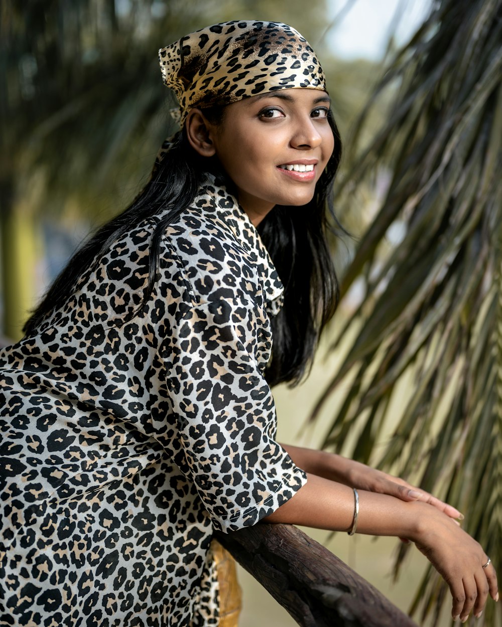 a woman in a leopard print dress leaning on a rail