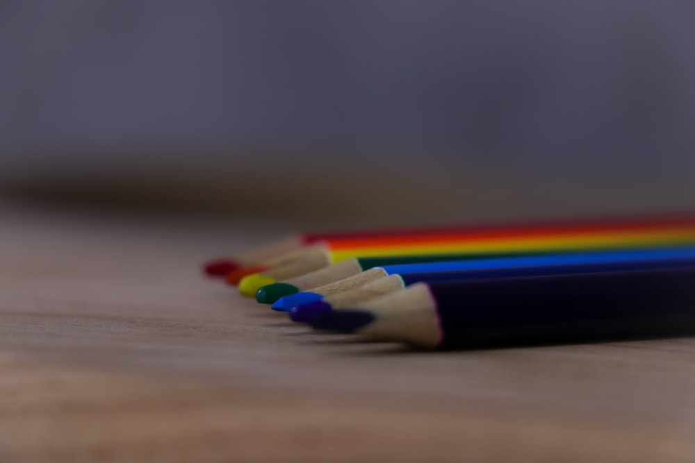 a group of colored pencils sitting on top of a wooden table