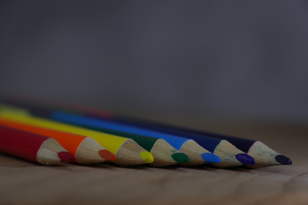 a row of colored pencils sitting on top of a wooden table
