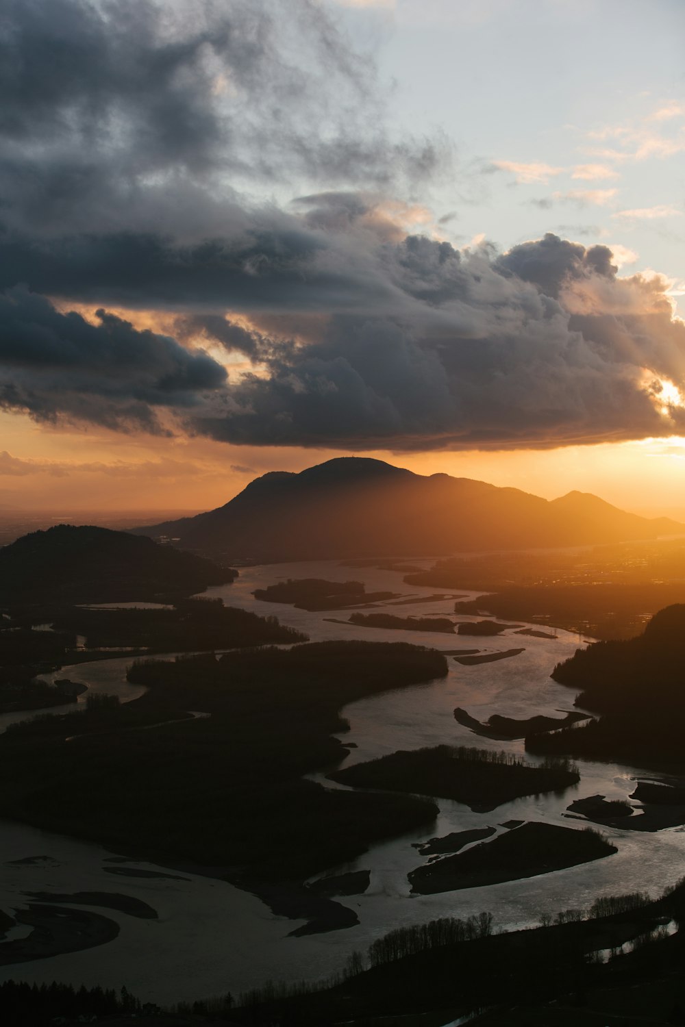 the sun is setting over a lake and mountains