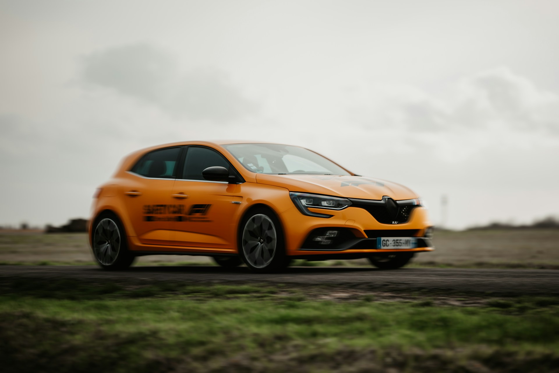 a bright orange car driving down a road