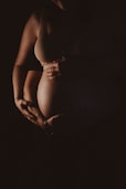 a pregnant woman holding her belly in the dark
