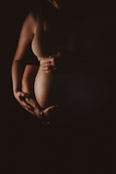 a pregnant woman holding her belly in the dark