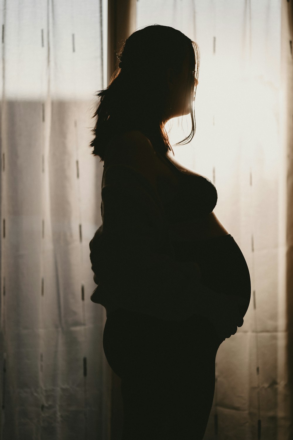 a pregnant woman standing in front of a window