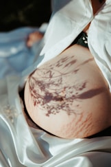 a pregnant woman's stomach with a tree shadow on it