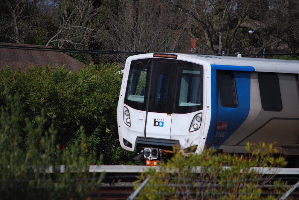 a white and blue train traveling down train tracks